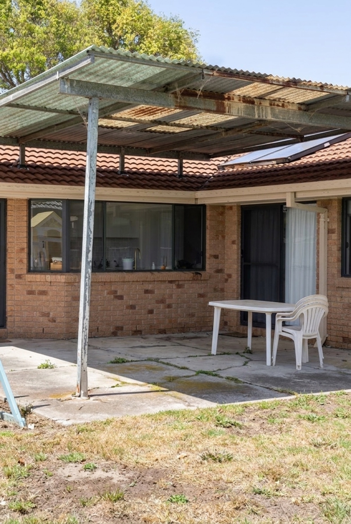 The same patio before — an old rusted fibreglass lean-to over cracked concrete