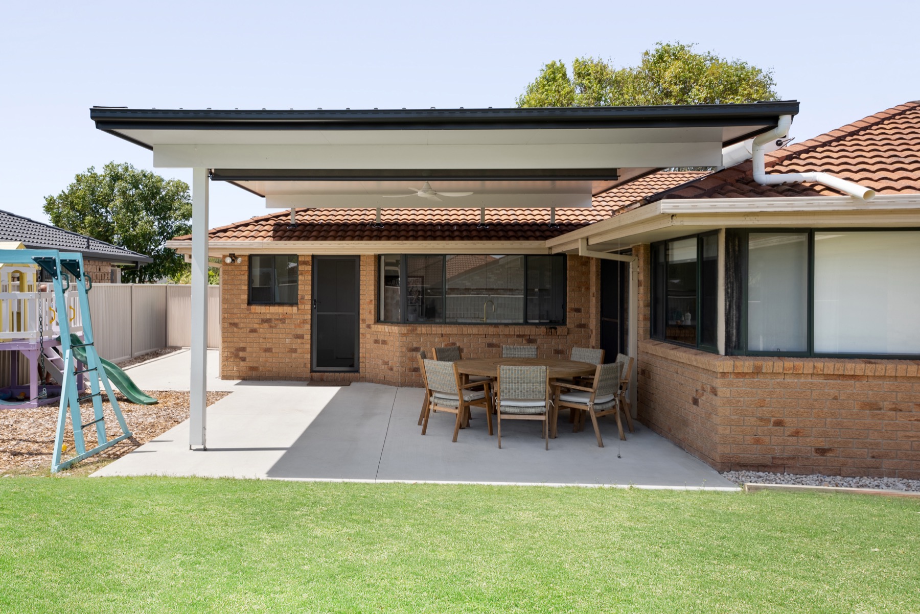 Flat-roof insulated patio over a concrete slab, attached to a brick home