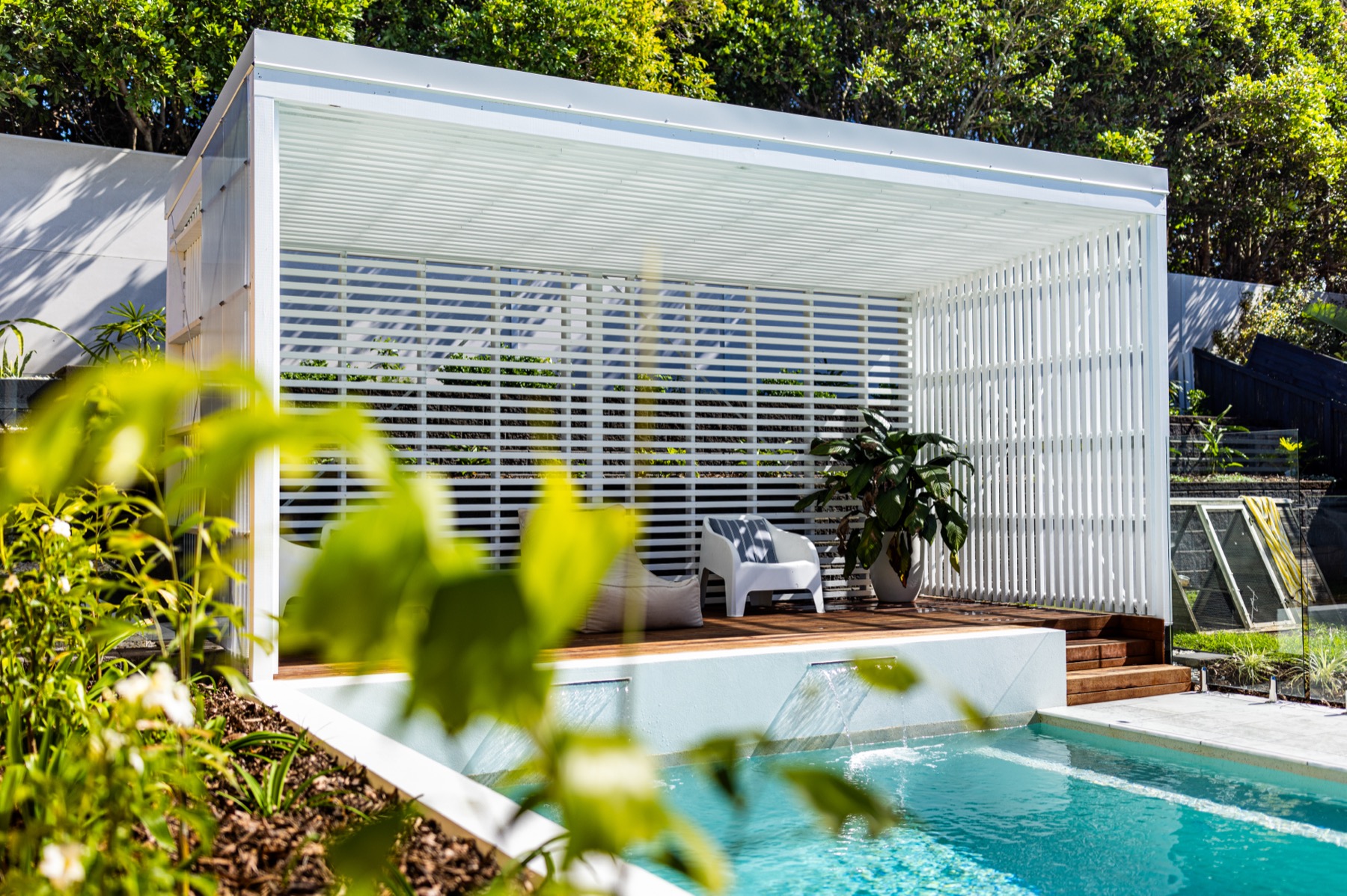 Freestanding louvred cabana beside a pool, over a timber deck